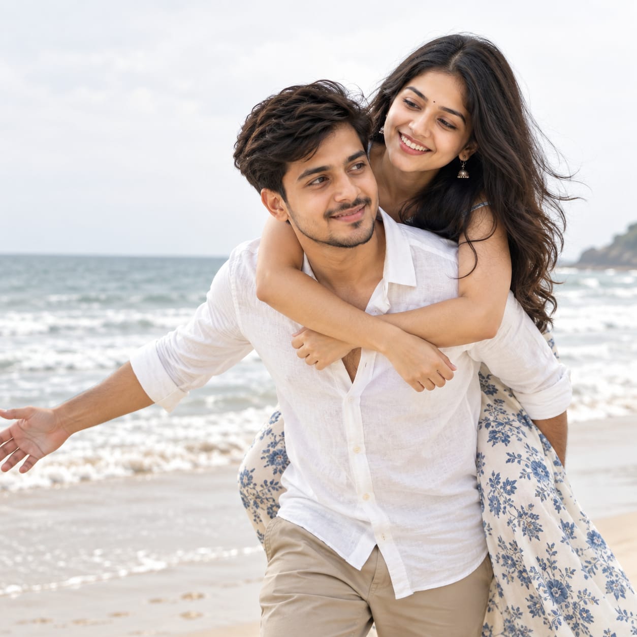 Indian pre-wedding couple enjoying a playful piggyback moment on a bright beach with a soft ocean horizon
